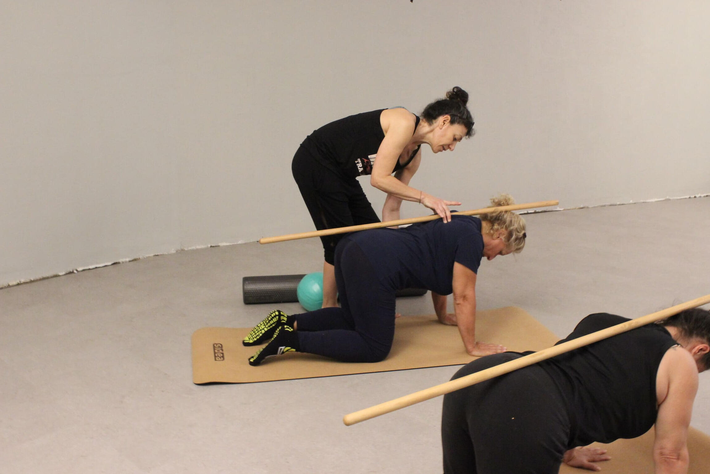 insegnante di pilates che corregge allieva esercizio con bastone
